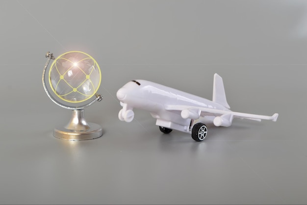 Самолет и хрустальный глобус на сером фоне Концепция путешествия Служба бронирования или знак туристического агентства Воздушный транспорт