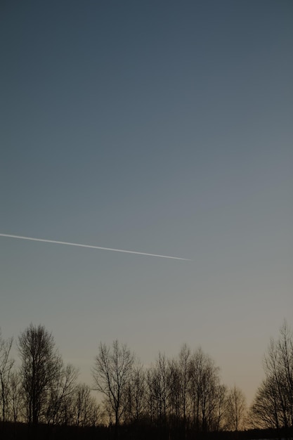 飛行機は夕焼け空を飛び、トレイルを離れる素晴らしいパノラマの日の出または夕焼けの空グラデーションカラースカイテクスチャ抽象的な自然の背景