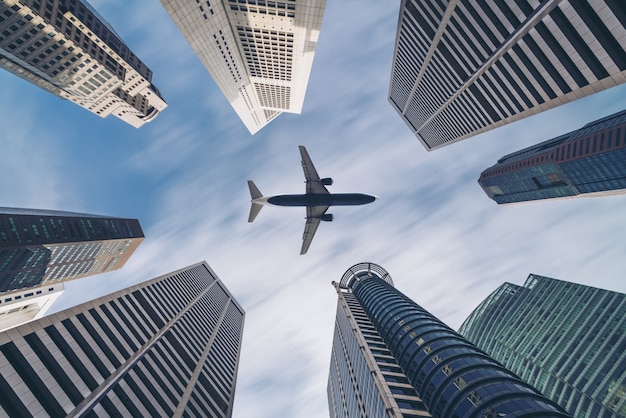 Airplane flying over city business buildings, high-rise skyscrapers