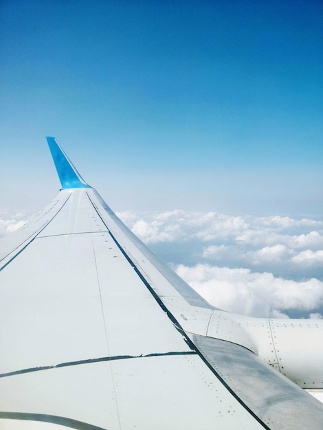 青い空を背景に雲の上を飛ぶ飛行機