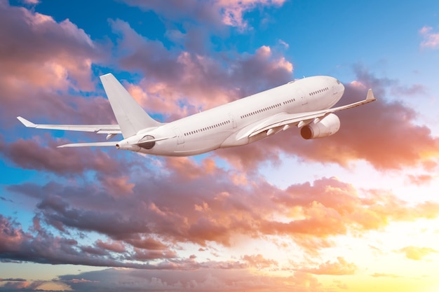 Airplane flying gaining height in the evening at sunset, the sky and picturesque clouds.