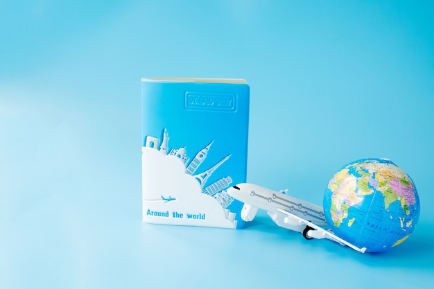 Photo airplane, globe and passport on blue background. summer or vacation concept.