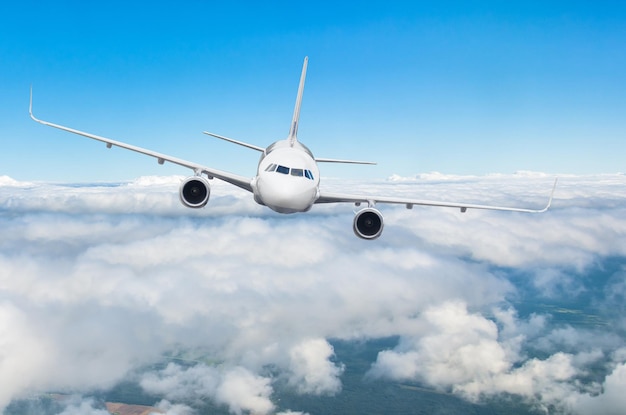 Airplane jet flying at flight level high in the sky above the clouds and blue sky