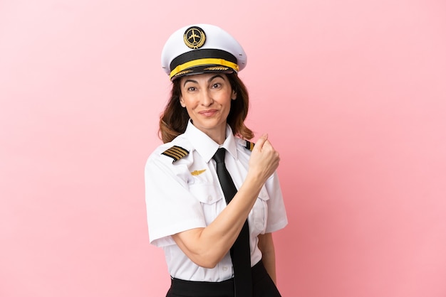 Airplane middle aged pilot woman isolated on pink background celebrating a victory