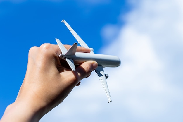 Airplane model in hand on sunny sky. Concepts of travel, transportation