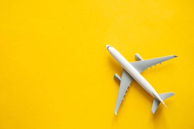 Airplane model on yellow background isolated flat lay air ticket travel and vacation concept copy space