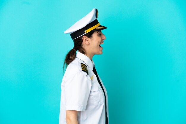 Foto pilota di aereo donna caucasica isolata su sfondo blu ridendo in posizione laterale