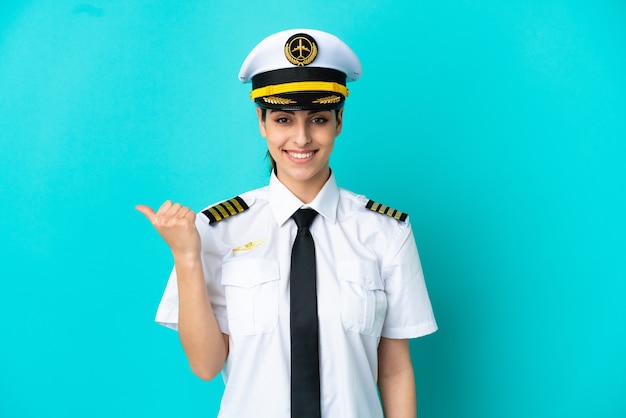 Airplane pilot caucasian woman isolated on blue background pointing to the side to present a product