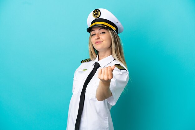 Photo airplane pilot over isolated blue background making money gesture