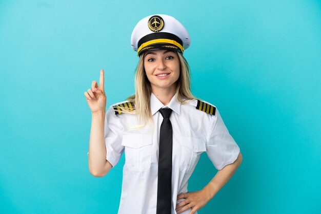 Airplane pilot over isolated blue background pointing up a great idea