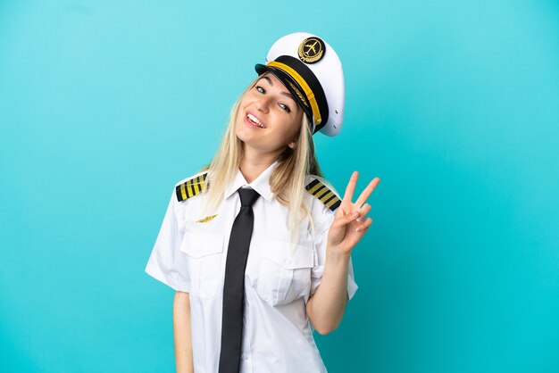Airplane pilot over isolated blue background smiling and showing victory sign