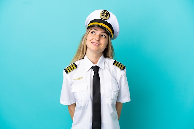 Airplane pilot over isolated blue background thinking an idea while looking up