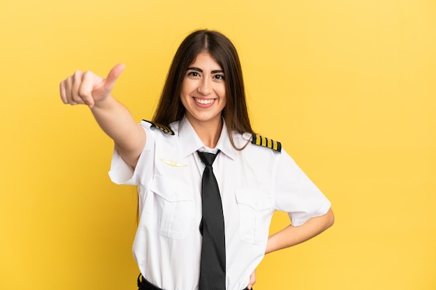 Airplane pilot isolated on yellow background giving a thumbs up gesture