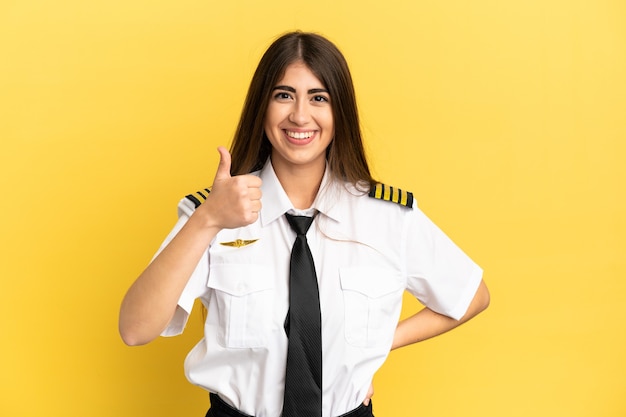 Airplane pilot isolated on yellow background giving a thumbs up gesture