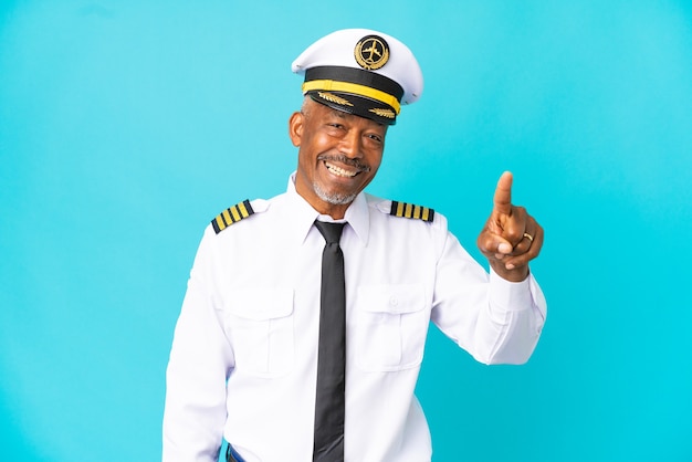 Airplane pilot senior man isolated on blue background surprised and pointing front