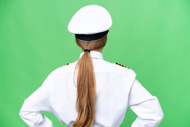 Photo airplane pilot woman over isolated chroma key background in back position