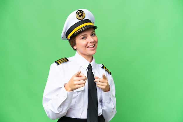 Женщина-пилот самолета на изолированном фоне хроматического ключа указывает вперед и улыбается