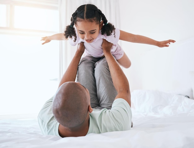 Airplane playful and father with daughter in bedroom for morning wake up and weekend Happy excited and funny with man and young girl playing in family home for happiness freedom and support