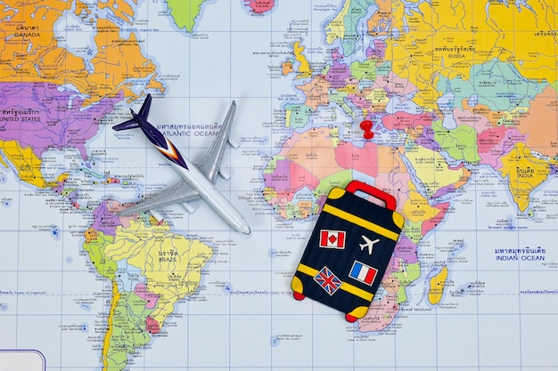 Airplane red push pin in world atlas as dream destinations and luggage bag tag with flags thai language translation in map traveling journey business trip travel concept life is fun