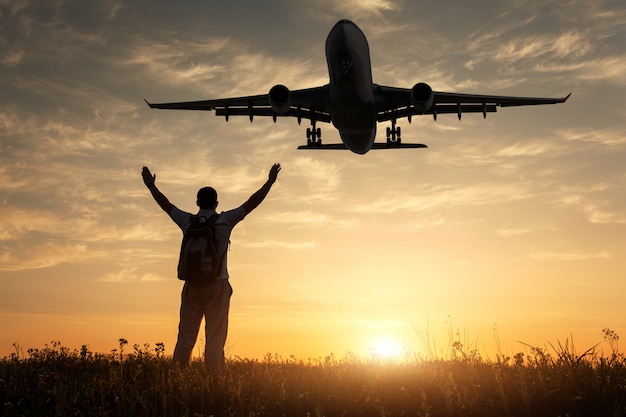 飛行機と立っている幸せな男のシルエット