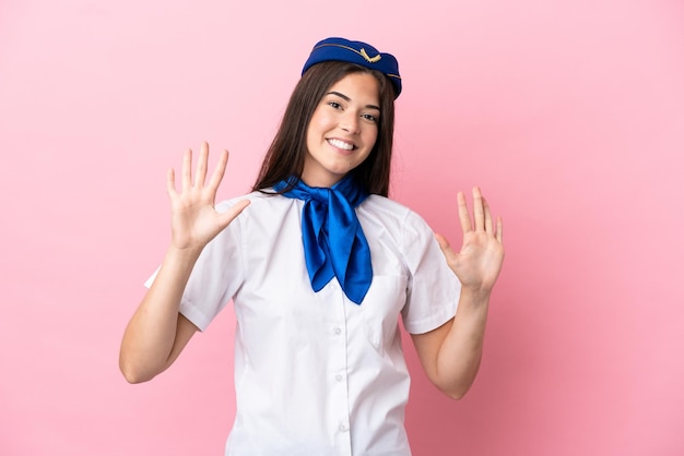 指で10を数えるピンクの背景に分離された飛行機のスチュワーデスブラジル人女性