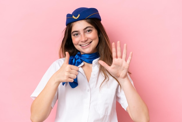 Airplane stewardess caucasian woman isolated on pink background counting six with fingers