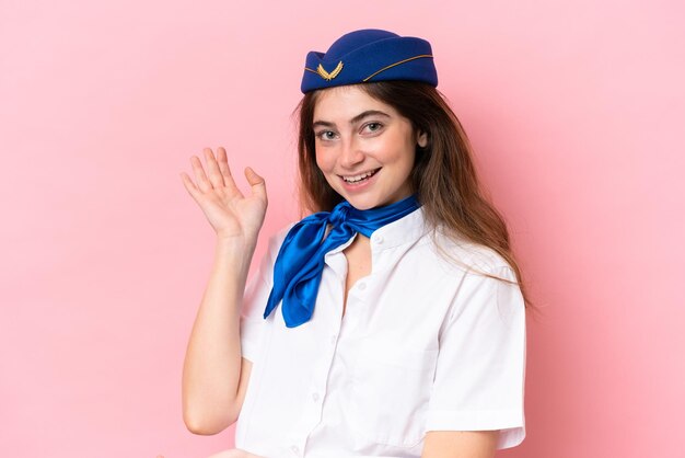 Foto hostess in aereo donna caucasica isolata su sfondo rosa che estende le mani di lato per invitare a venire