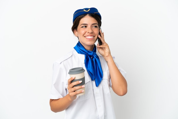 Hostess aereo donna caucasica isolata su sfondo bianco tenendo il caffè da asporto e un mobile