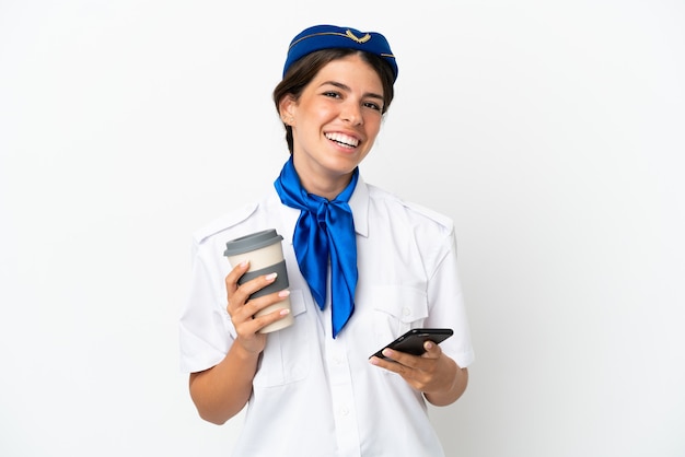 Airplane stewardess caucasian woman isolated on white background holding coffee to take away and a mobile