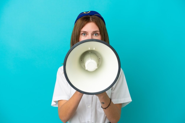 Airplane stewardess English woman isolated on blue background shouting through a megaphone