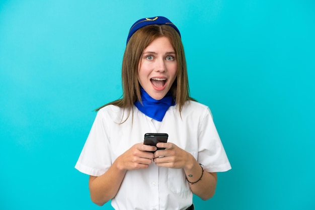 Airplane stewardess English woman isolated on blue background surprised and sending a message