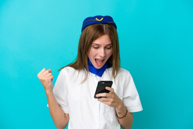 Airplane stewardess English woman isolated on blue background surprised and sending a message