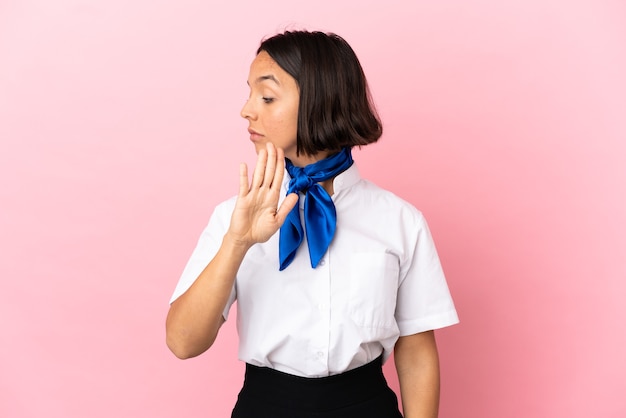 Airplane stewardess over isolated background making stop gesture and disappointed