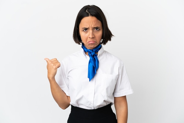 Airplane stewardess over isolated background unhappy and pointing to the side