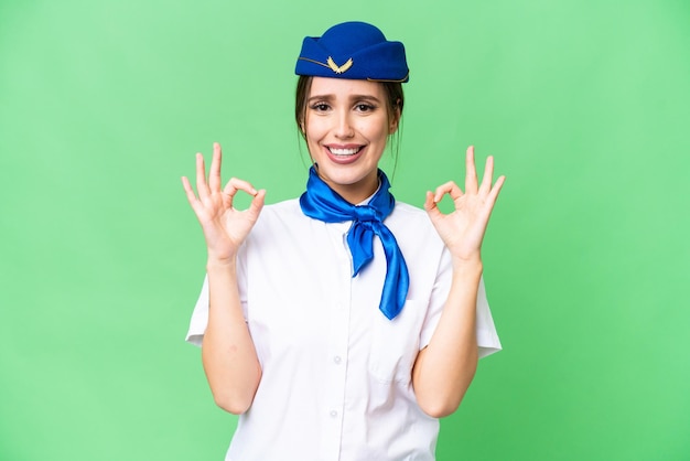 Hostess in aereo su sfondo chroma key isolato che mostra un segno ok con le dita