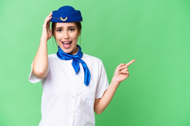 Foto hostess dell'aeroplano su sfondo chroma key isolato sorpreso e puntando il dito di lato