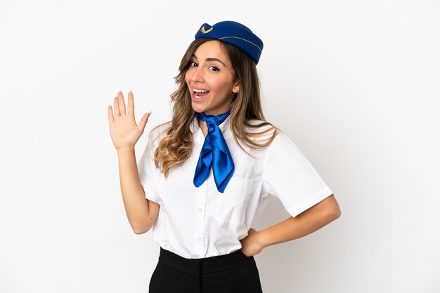 Airplane stewardess over isolated white background saluting with hand with happy expression