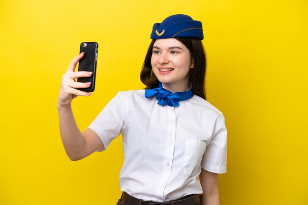 Airplane stewardess russian woman isolated on yellow background making a selfie