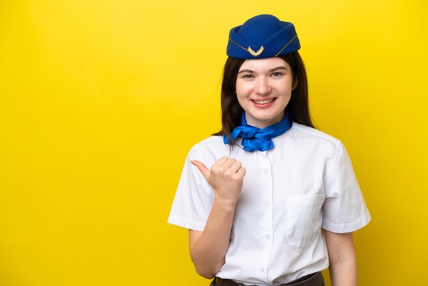 Airplane stewardess Russian woman isolated on yellow background pointing to the side to present a product