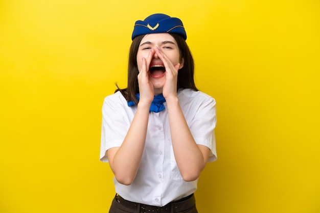 노란색 배경에 격리된 비행기 스튜어디스 러시아 여성이 소리를 지르며 무언가를 발표합니다.