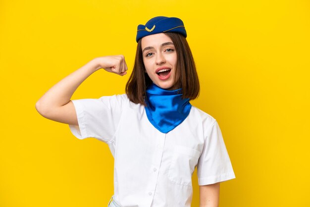 Airplane stewardess Ukrainian woman isolated on yellow background doing strong gesture