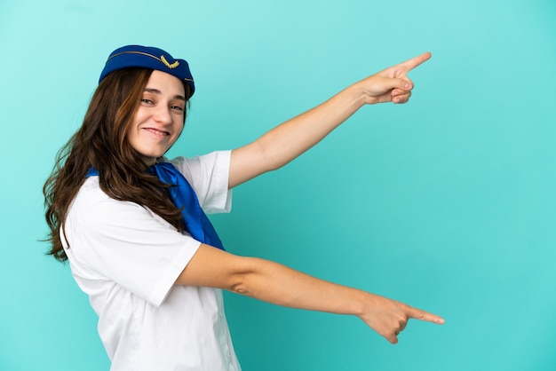 Airplane stewardess woman isolated on blue background pointing finger to the side and presenting a product