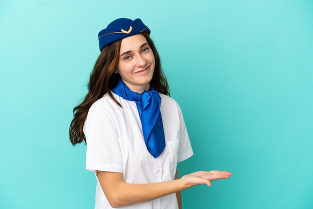 Airplane stewardess woman isolated on blue background presenting an idea while looking smiling towards