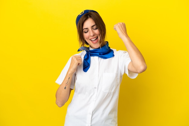 Airplane stewardess woman isolated on yellow background celebrating a victory