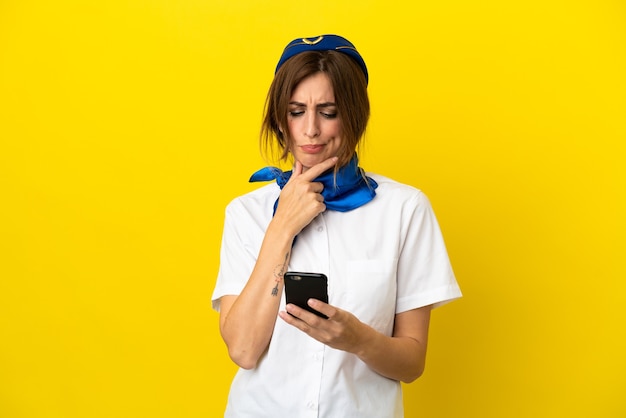 Airplane stewardess woman isolated on yellow background thinking and sending a message