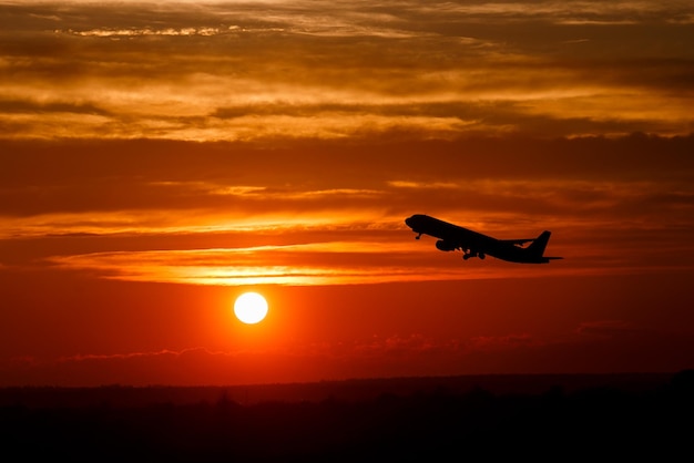 Foto aeroplano al cielo al tramonto sul sole in aria con spazio per il testo silhouette di aerei in volo alla luce del sole concetto di trasporto aereo che decolla nel cielo drammatico incredibile immagine atmosferica