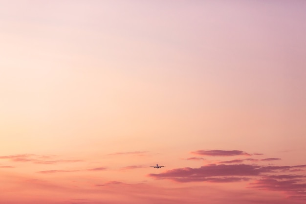 Aereo che decolla e sale in alto nel concetto di vacanza rosa del cielo al tramonto