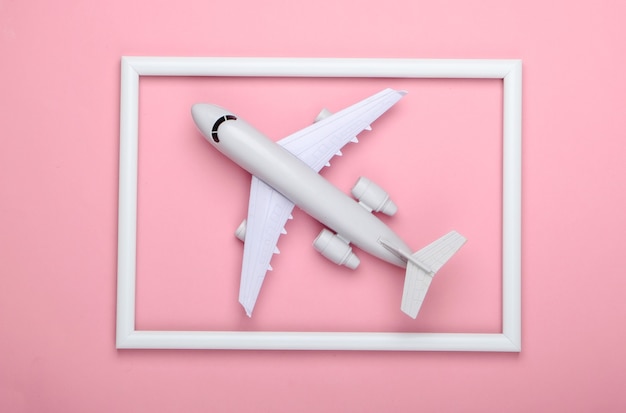 Airplane in a white frame on pink surface