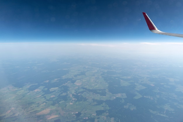 Airplane window view to cloudy sky and earth