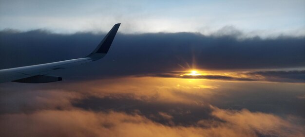 写真 太陽が昇る際の空に向かう飛行機の翼